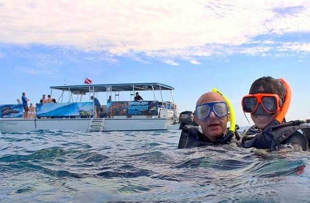 couple snorkeling near a charter boat at barefoot billys key west