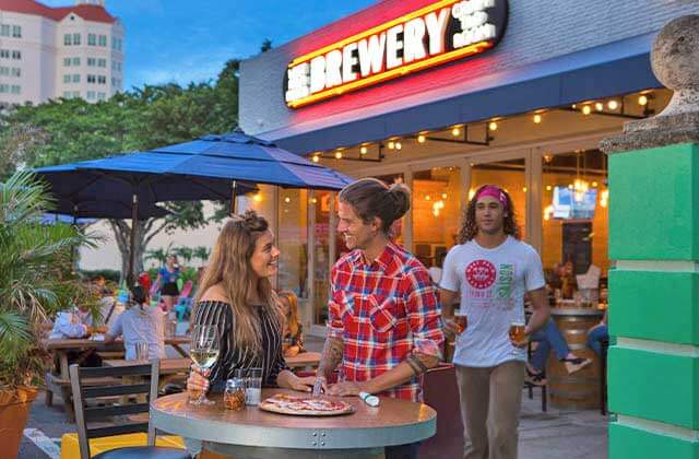 couple standing at high-top table on patio of brewery at twilight at ale trail of the palm beaches