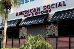 exterior building sign with black awnings and palm trees at american social orlando