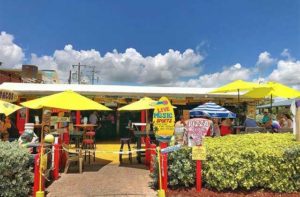 exterior of restaurant with outdoor seating and yellow umbrellas at sandbar sports grill cocoa beach