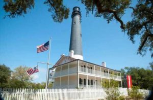 exterior view of a white two story historic house with lighthouse behind at pensacola lighthouse florida