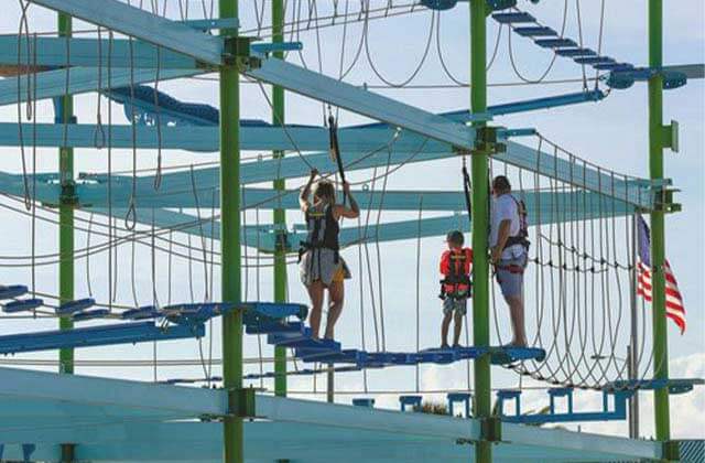 family traversing a ropes course on an elevated structure at lagunas beach bar grill pensacola
