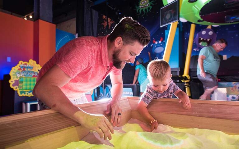 father and son interacting with sandbox at wonderworks panama city beach