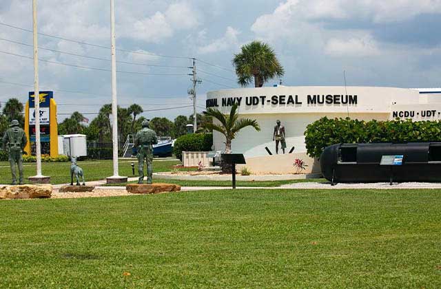 front exterior of building with statues and flags at national navy udt seal museum ft pierce