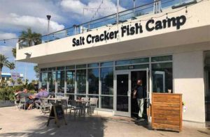 front exterior of nautical themed building with sign and outdoor seating at salt cracker fish camp clearwater