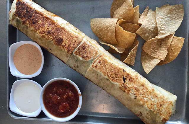giant burrito in a tray with three sauces and chips at epic beach bar grill cocoa beach