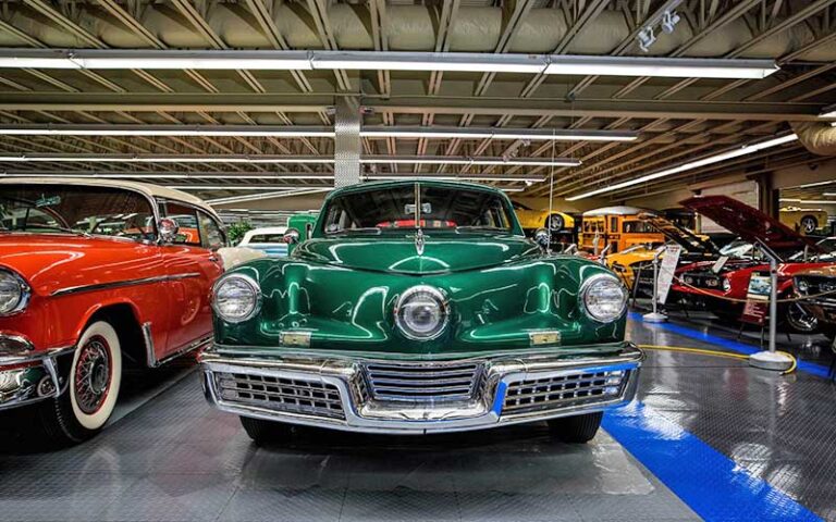 green classic car with red cars and walkway at tallahassee automobile museum
