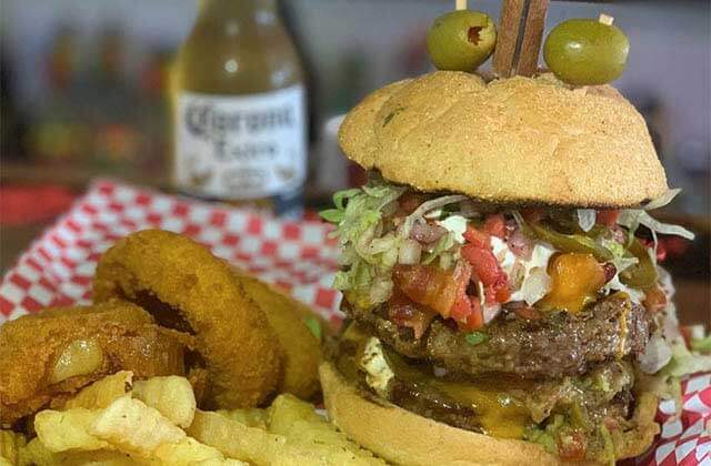 huge double burger with steak knife olives onion rings fries and beer at sandbar sports grill