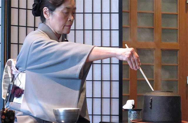 a japanese woman stirs tea in traditional attire at morikami museum japanese gardens delray beach