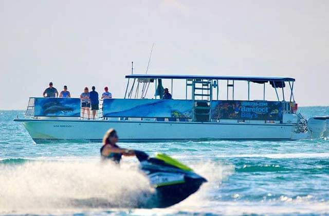 large charter boat with jet skier passing at barefoot billys key west