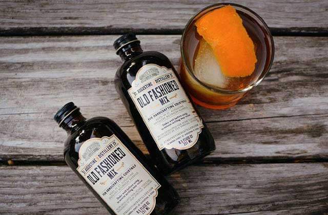 old fashioned drink with orange rind and two bottles of branded mixer at st augustine distillery