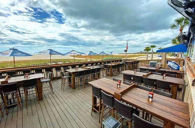 outdoor patio overlooking beach with tables chairs blue and white umbrellas at sloppy joes treasure island