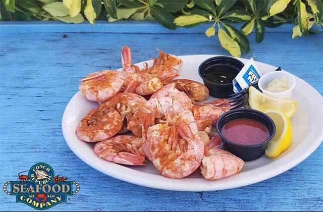 platter of large shrimp with sides on a blue wooden bar outside at conch republic seafood company key west