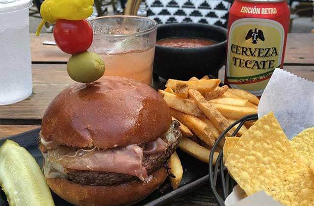 signature burger with sides and foreign beer on an outdoor table at taberna del caballo st augustine