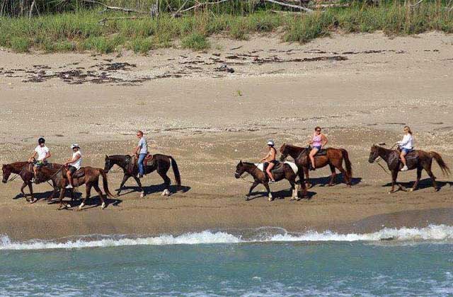 six horseback riders riding along a beach at tours on horseback st lucie florida