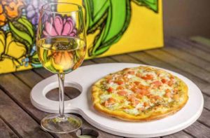 small pizza on artists palette plate with glass of white wine at pizza gallery grill melbourne florida