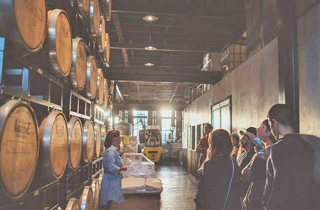 tour guide leading a group through a room with huge barrels and a fork lift at st augustine distillery