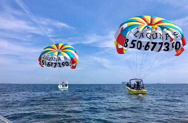 two boats in the ocean with colorful parasail chutes open at lagunas beach bar grill pensacola