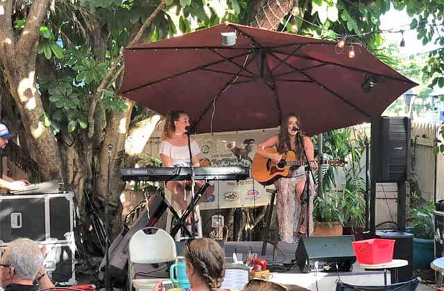 two women playing guitar and piano performing on stage outside at viva argentinean steakhouse key west