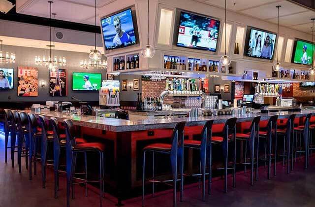 upscale bar with screens red lighting and black stools at american social orlando