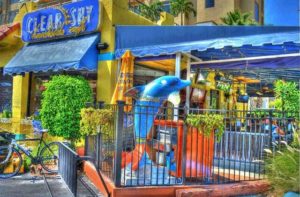 yellow and blue exterior of restaurant with patio and dolphin statue at clear sky beachside cafe clearwater