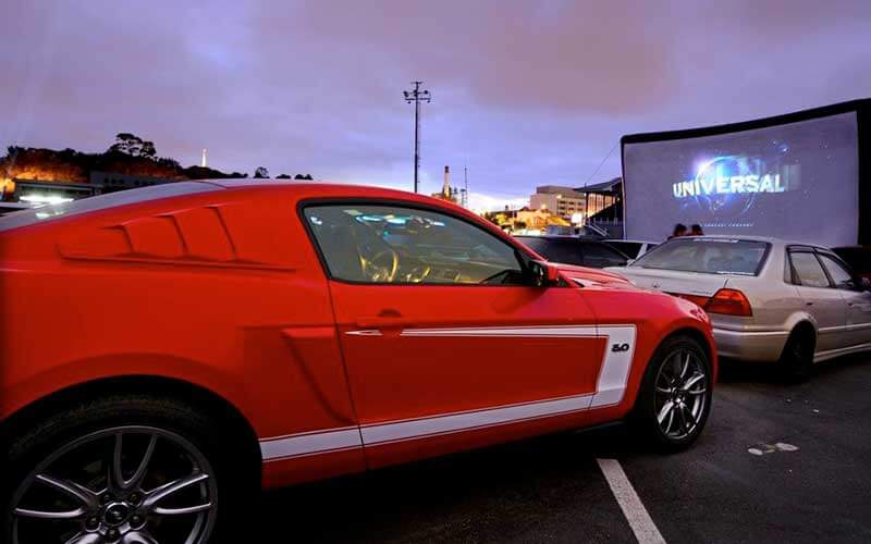 red car parked at drive in movie screen in twilight for old town hosts halloween drive in movies post