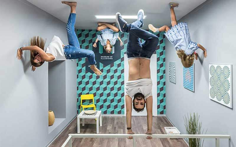 people appear upside down in a room one girl doing yoga one man holding onto a bar