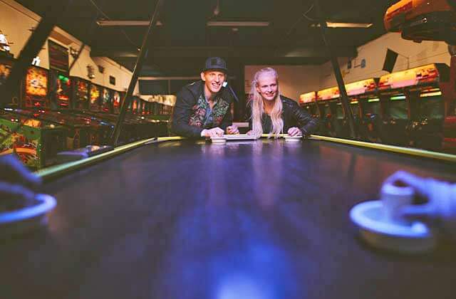 boy and girl playing air hockey in a room full of pinball games at fun games arcade kissimmee