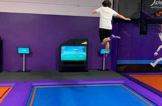 boy jumping on trampoline pad while playing an interactive game on screen at altitude trampoline park kissimmee