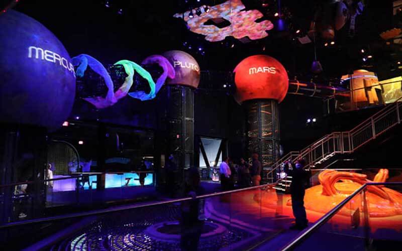 dark room with space and planets lit up at planet play at kennedy space center visitor complex