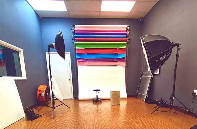 empty photography studio with multi-colored backdrops lighting fan and stool at avc photo store school miami