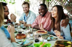 diverse smiling adults eat thanksgiving meal outdoors in orlando