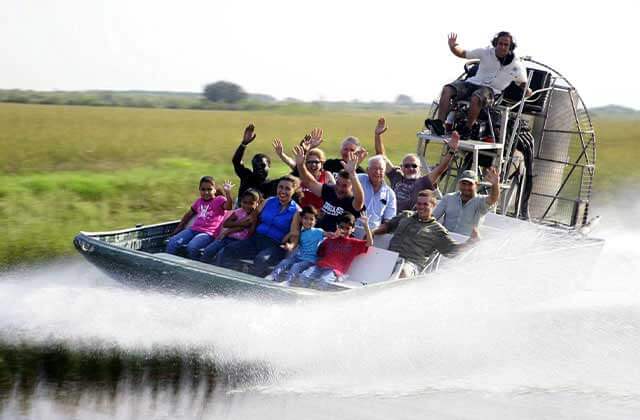 group waving from speeding airboat tour on a marsh at real florida adventures