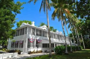 large white home with miami shutters red and blue banners and palm trees at harry s truman little white house key west