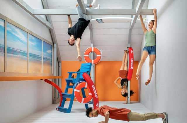 beach themed room with teens in various positions hanging upside down and sideways at museum of illusions icon park orlando