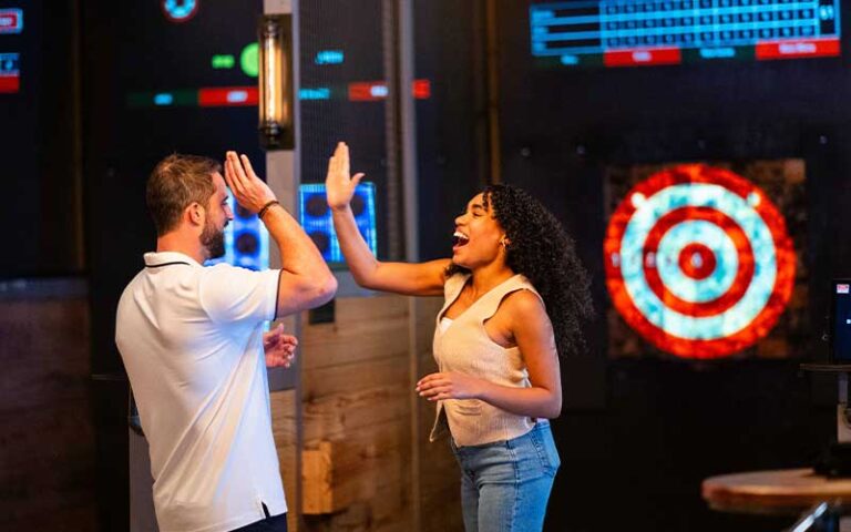 man and woman high fiving in axe throwing area at dezerland park orlando