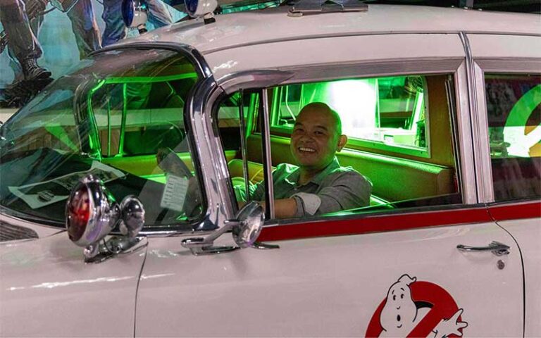 man seated in drivers seat of ghostbusters vehicle at orlando auto museum at dezerland park