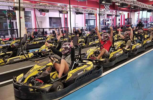 rows of go karts with helmeted drivers with thumbs up at dezerland park orlando