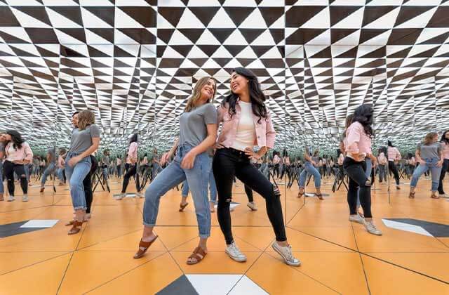 two girls in a hall of mirrors with checkerboard and orange design at museum of illusions icon park orlando
