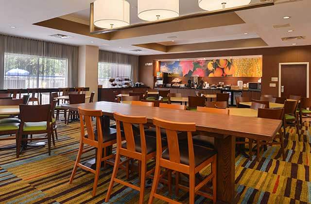 breakfast and dining area with high-top tables chairs buffet area and colorful carpet and decor at fairfield inn orlando airport