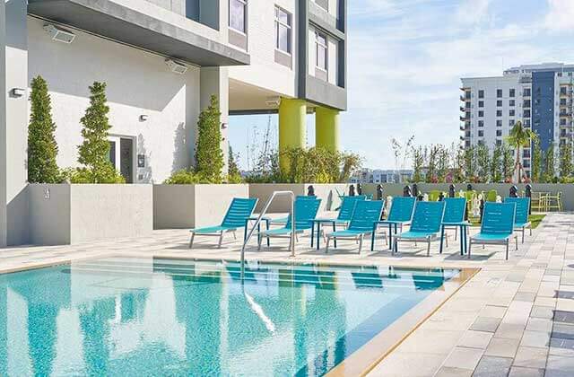 bricked pool deck area with rows of blue chaise lounges at tru by hilton ft lauderdale airport