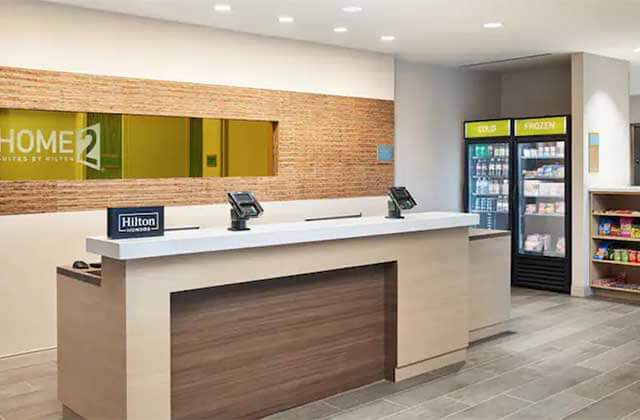 check-in desk and snack counter with stone tile floor and wood panel at home2 suites by hilton palm bay i-95