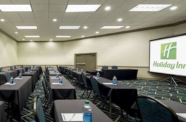 conference media room with projector and long tables with water bottles at holiday inn palm beach airport conference center