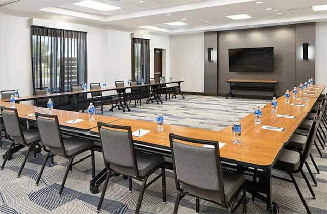 conference room with long tables water bottles pads paper pens and a large screen at hyatt place melbourne palm bay florida