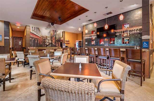 dining area and bar with wood and wicker accents at best western plus palm beach gardens hotel and suites conference center