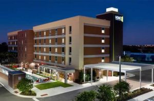 exterior of hotel at night in brown with green accents at home2 suites by hilton orlando near ucf
