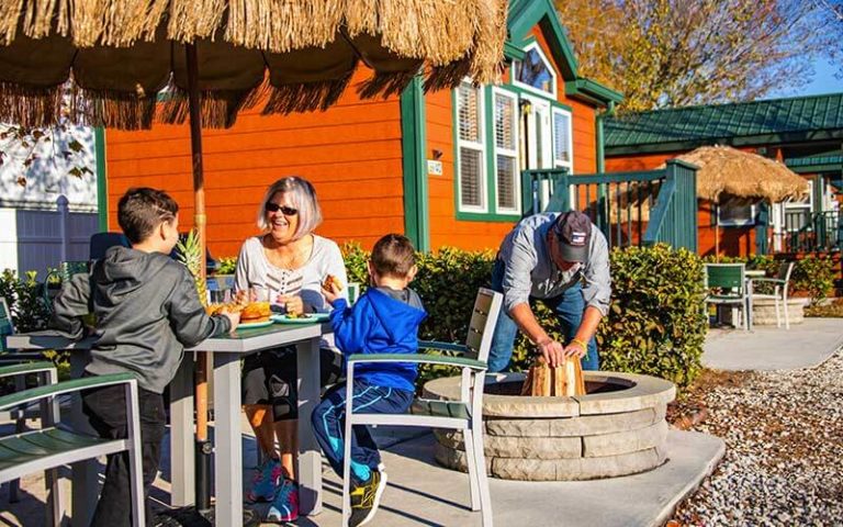 family eating and talking with orange cabins in the background at orlando kissimmee koa holiday