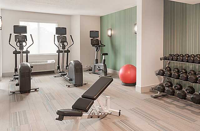 fitness center with dumbbells ellipticals and benches at holiday inn express and suites nearest universal orlando