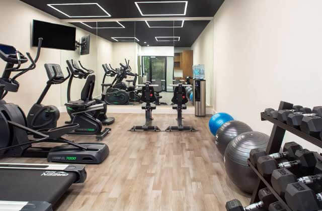 fitness room with dumbbells yoga balls mirrors and cardio equipment at wyndham garden ft lauderdale airport and cruise port