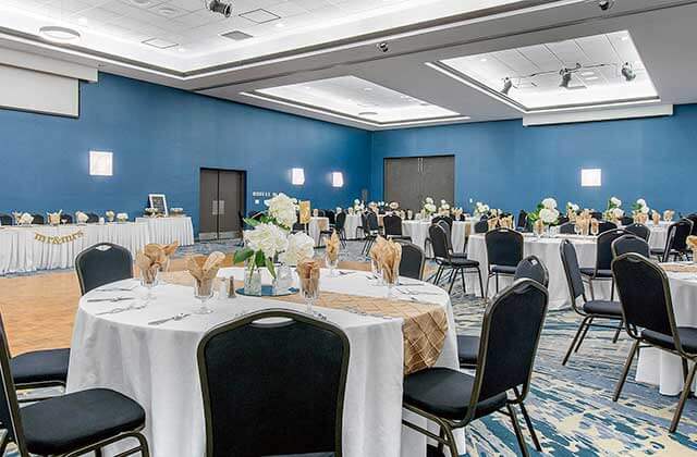 formal dining banquet room with blue walls gold accents tables and chairs at holiday inn melbourne viera conference center